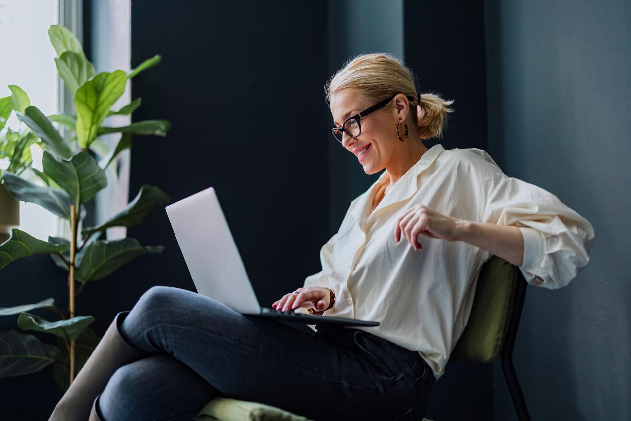 happy woman working on laptop browsing Chubb's Risk Consulting Library